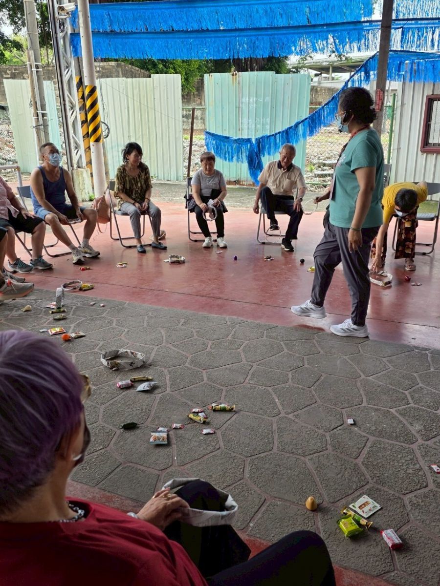 長者於據點使用自製報紙圈圈搭配地上目標物,訓練下肢協調與認知判斷。